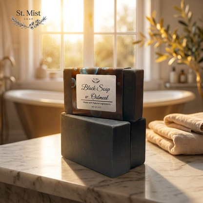 St. Mist Soap black oatmeal bar with activated charcoal, displayed on a marble counter in a sunlit bathroom.